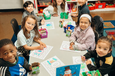 A group of kindergartners works on a winter art project with a parent volunteer